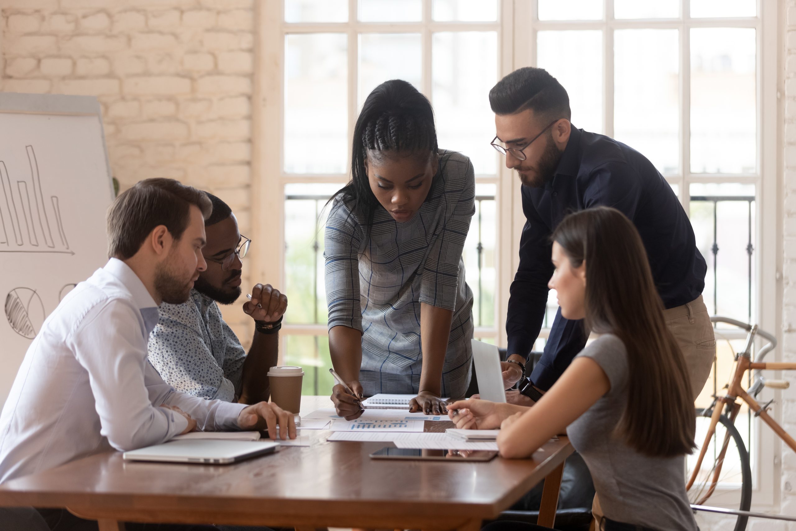 five employees around a conference table looking at charts